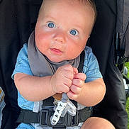 Grayson is registered to the contest to win money with this photo: baby, child, blue_eyes, stroller, toy, beads, clothing, cute, infant, hands, face, rosy_cheeks, seatbelt, outdoor, curious, expression, summer_clothing, legs, person, closeup