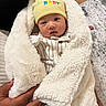 baby, blanket, yellow_hat, hands, indoor, floor, rug, wood, cozy, cute, infant, clothing, person, face, portrait, warm, soft, wrapped, newborn, comfortable