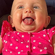Jasmine is registered to the contest to win money with this photo: baby, infant, child, smiling, tongue_out, pink_clothing, polka_dot, car_seat, safety_harness, happy, cute, face, cheeks, eyes, playful, indoor, closeup, person, seatbelt, toy