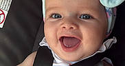 Sofia is registered to the contest to win money with this photo: baby, smiling, headband, car_seat, child, infant, happy, cute, hand, clothing, eyes, face, seatbelt, toddler, portrait, blue, fabric, sitting, closeup, indoor