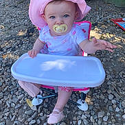Sofia joined the competition — help win amazing prizes! baby, child, pacifier, pink_hat, outdoor, sun_hat, high_chair, blue_eyes, clothing, footwear, rocky_ground, reaching_hand, seat, summer, cute, infant, expression, sunlight, nature, young