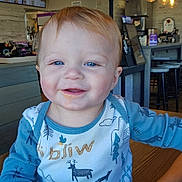 Sawyer joined the competition — help win amazing prizes! baby, child, smiling, blue_eyes, food_on_face, long_sleeve_shirt, pants, indoor, restaurant, wooden_table, lights, decor, happy, cute, sitting, person, face, portrait, infant, cozy