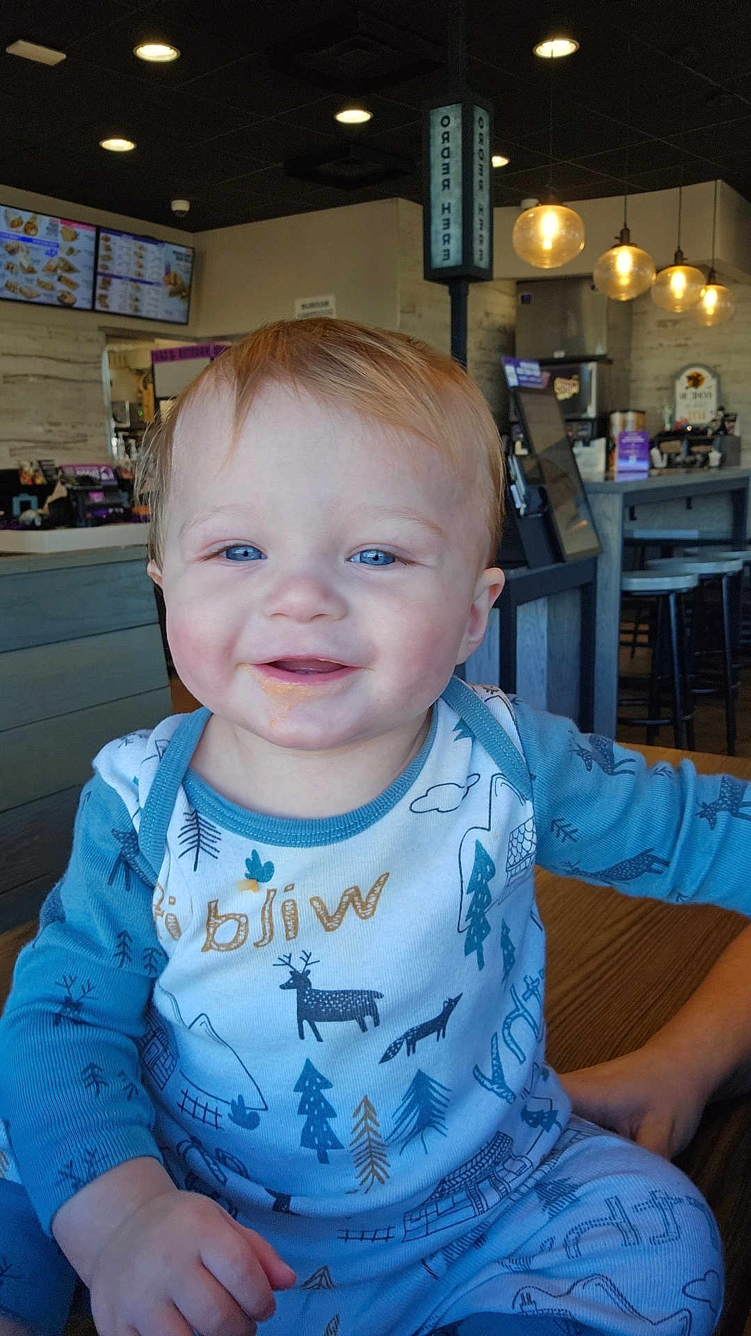 Sawyer joined the competition — help win amazing prizes! baby, child, smiling, blue_eyes, food_on_face, long_sleeve_shirt, pants, indoor, restaurant, wooden_table, lights, decor, happy, cute, sitting, person, face, portrait, infant, cozy