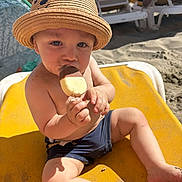 Liam participe au concours pour gagner de l'argent avec cette photo : toddler, child, hat, straw_hat, ice_cream, beach, sand, sunlight, yellow_chair, swim_shorts, summer, outdoor, relaxing, vacation, cute, portrait, food, happy, sitting, beach_chair