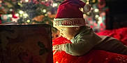 Gideon joined the competition — help win amazing prizes! baby, child, santa_hat, christmas_tree, holiday, book, blanket, red, cozy, indoors, festive, lights, decorations, warm, face, portrait, holiday_season, cute, curious, celebration