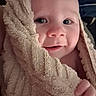 baby, towel, face, child, skin, hand, smile, close_up, portrait, soft_texture, wrapped, cute, infant, warm, comfort, expression, eyes, indoors, cozy, young