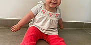 Léna participe au concours pour gagner de l'argent avec cette photo : baby, child, sitting, floor, headband, red_pants, white_top, smiling, indoor, cute, portrait, person, happy, tiled_floor, young_child, infant, casual_clothing, headwear, barefoot, playful