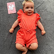 Léna participe au concours pour gagner de l'argent avec cette photo : baby, infant, smiling, headband, coral_outfit, ruffles, milestone_card, pink_card, gray_blanket, lying_down, cute, child, soft_texture, happy, portrait, indoors, skin, small_hands, small_feet, head