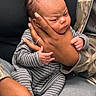 Zaylen joined the competition — help win amazing prizes! baby, newborn, infant, striped_onesie, hand, adult, holding, cradling, care, affection, tenderness, portrait, person, clothing, sitting, closeup, skin, face, expression, comfort