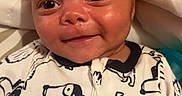 Zaylen is registered to the contest to win money with this photo: baby, infant, smile, face, onesie, dog_pattern, clothing, bed, blanket, soft, cute, child, portrait, happy, young, skin, head, eyes, indoor, cozy