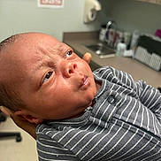 Zaylen is registered to the contest to win money with this photo: baby, newborn, infant, person, face, clothing, striped_onesie, hand, hospital, sink, cabinet, skin, expression, portrait, close_up, newborn_clothing, indoor, medical, care, holding