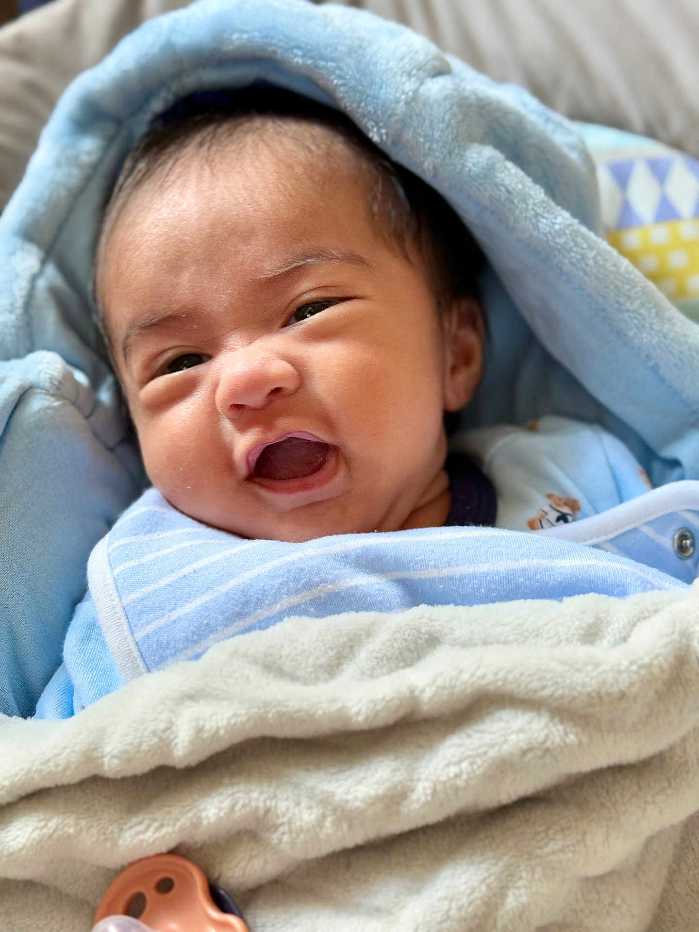 Josh Caleb is registered to the contest to win money with this photo: baby, blanket, blue, pacifier, face, expression, infant, clothing, cute, soft, wrapped, indoors, closeup, newborn, smile, lying_down, nap, baby_bib, child, portrait