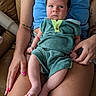 adult, baby, casual, child, clothing, couch, face, green_outfit, hand, indoor, infant, leather, legs, nail_polish, person, portrait, sitting, skin, tank_top, tattoo