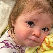 Novie is registered to the contest to win money with this photo: child, baby, infant, face, cheek, eyes, brown_eyes, hair, blanket, yellow_blanket, onesie, pattern, closeup, portrait, sleepy, drool, rosy_cheeks, indoors, soft_texture, cuddling