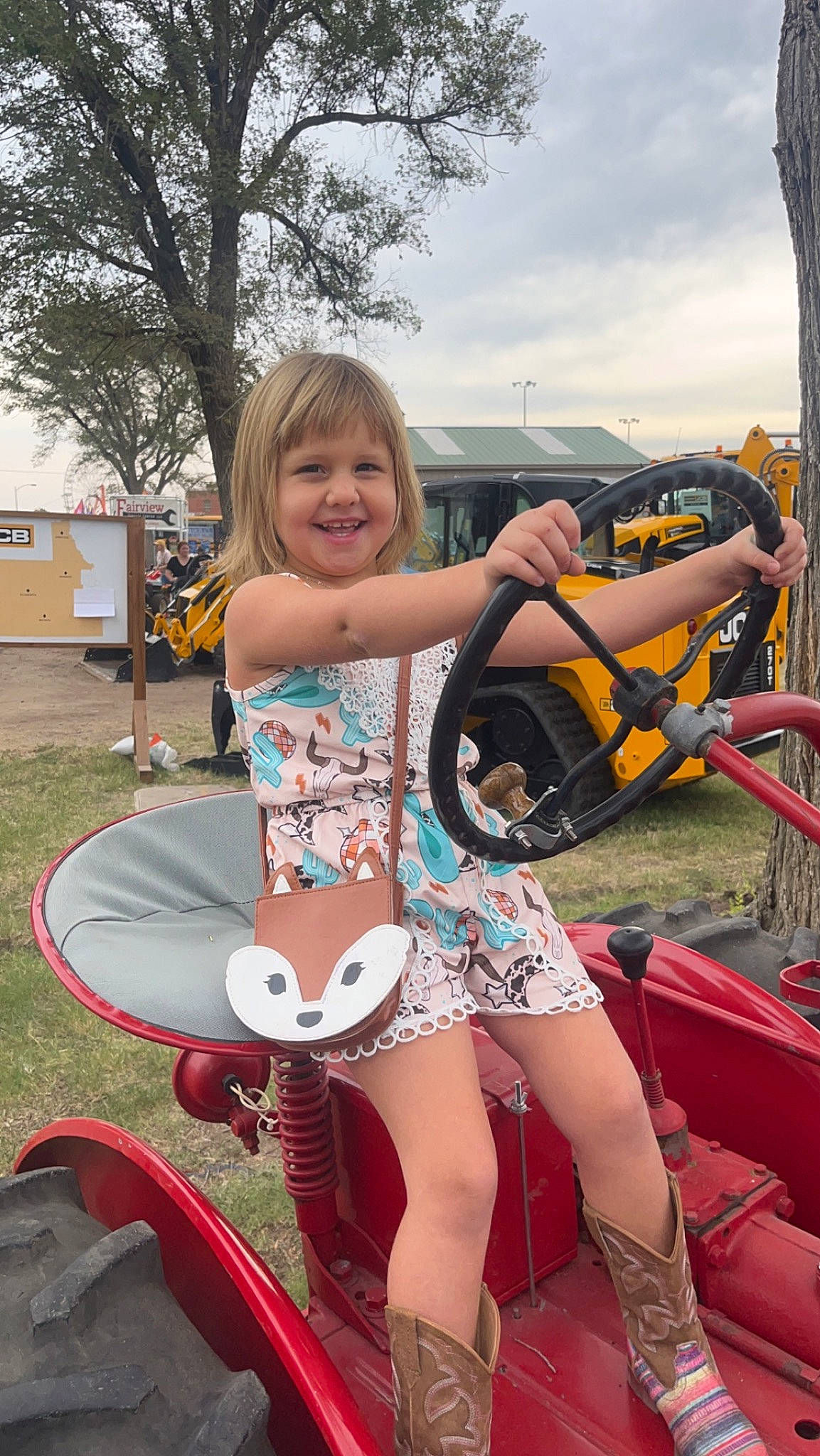 Kensley is registered to the contest to win money with this photo: automotive_design, automotive_exterior, automotive_tire, bumper, fender, fun, grass, joy, leg, motor_vehicle, person, pink, shorts, sky, smile, steering_wheel, summer, thigh, tire, tree