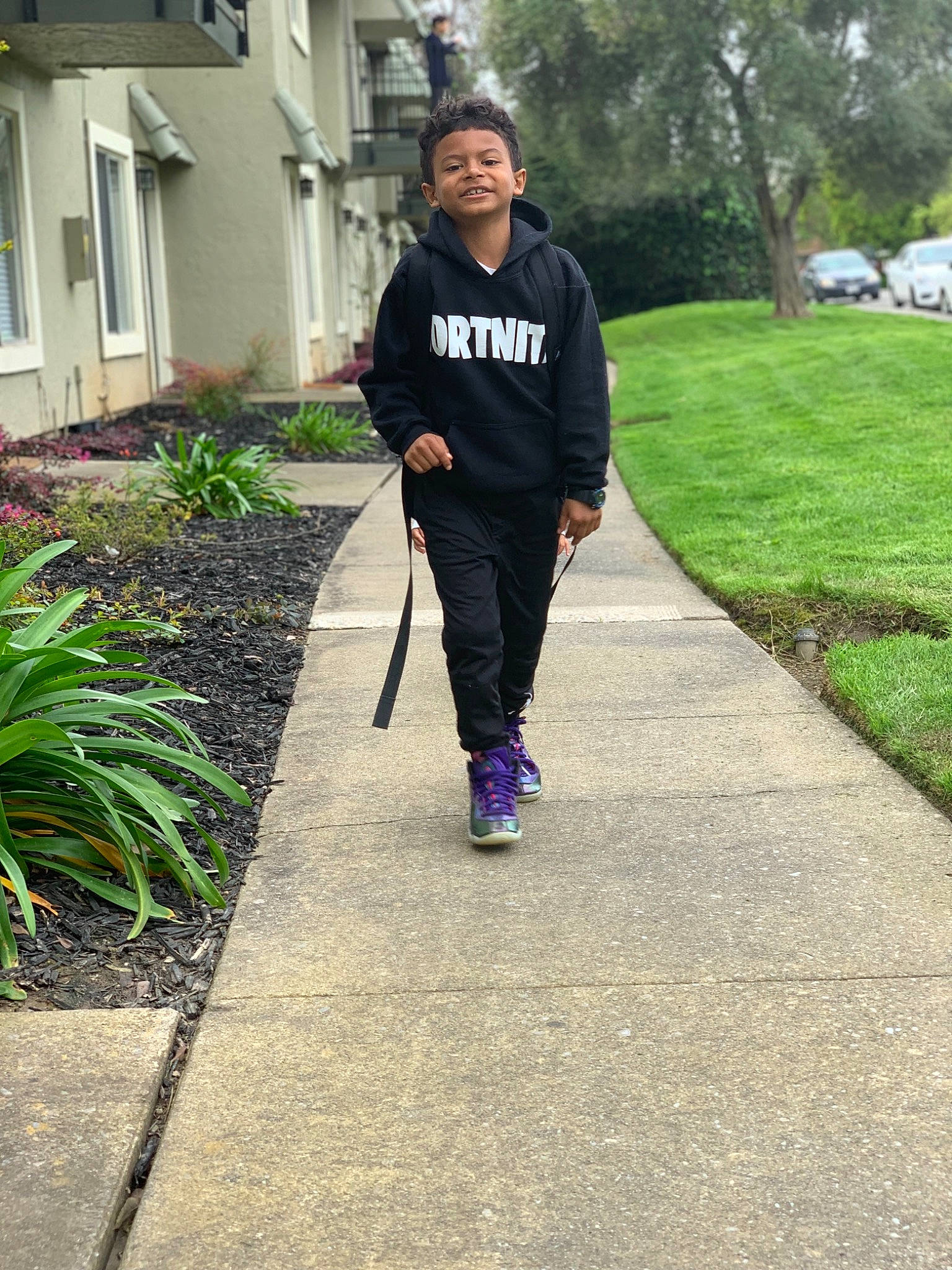 Josiah is registered to the contest to win money with this photo: asphalt, garden, grass, lawn, outerwear, person, plant, recreation, shoe, sidewalk, tree, trousers, walking, walkway