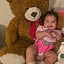 Hanna is registered to the contest to win money with this photo: baby, carpet, child, childhood, comfort, cute, furry, happy, indoor, pink_clothing, plush_toy, portrait, red_bow, sitting, small_pony_tail, smiling, socks, soft, teddy_bear, toy