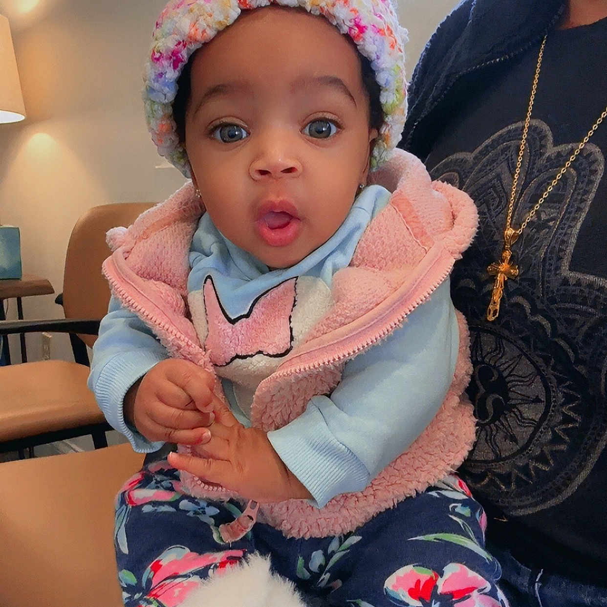Azura joined the competition — help win amazing prizes! adult, baby, blue_sweater, chair, child, colorful_clothing, cute, expression, floral_pants, furniture, hat, home, indoor, lamp, lap, person, pink_vest, portrait, surprise, white_boots