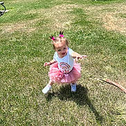 Leilani joined the competition — help win amazing prizes! toddler, child, grass, outdoor, sunny, pink_tutu, white_sneakers, hair_bows, shadow, reaching, playful, smiling, young_child, park, summer, greenery, happy, cute, daylight, fun