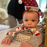 Jaxon joined the competition — help win amazing prizes! baby, child, infant, christmas_hat, holiday, festive, santa_hat, sweater, cute, smiling, face, hands, indoor, cozy, cushion, holiday_season, person, portrait, reaching, soft_focus