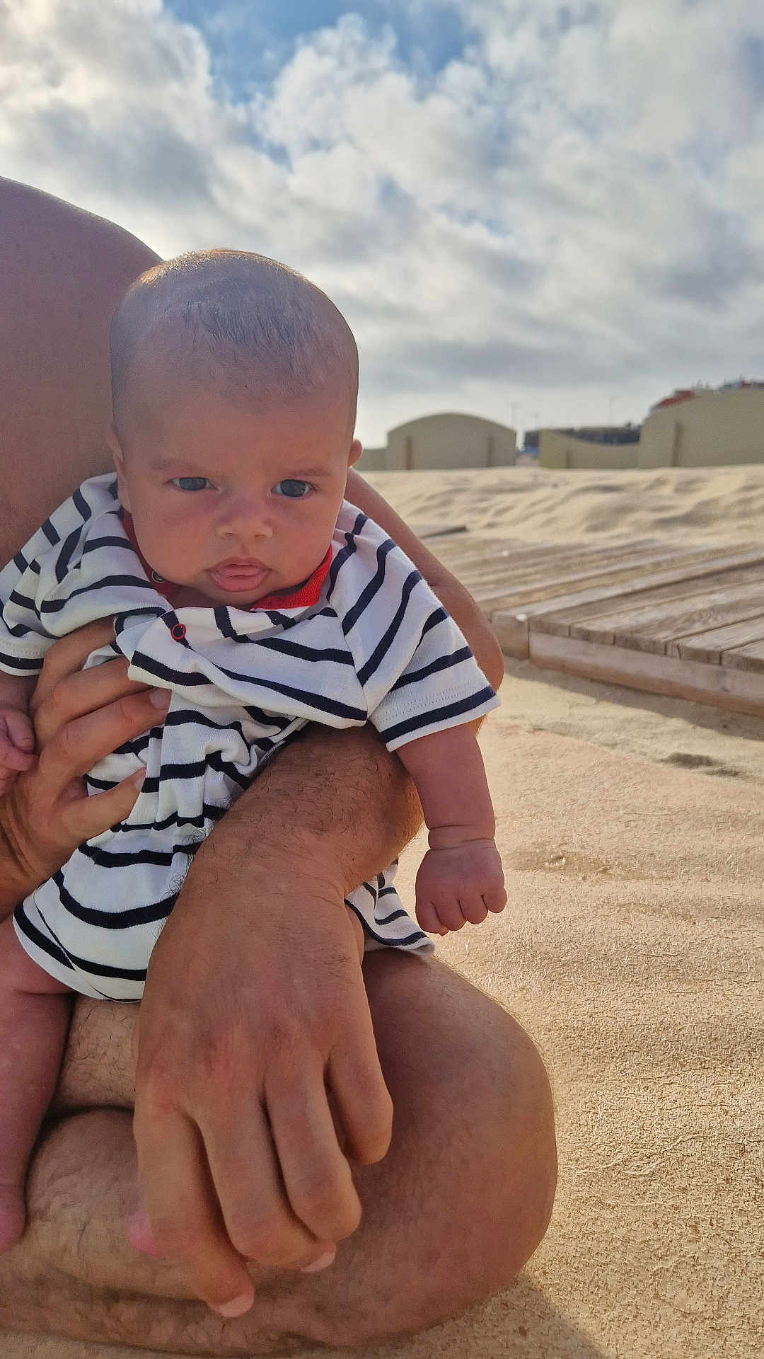 Lorenzo a rejoint le concours — aidez-le/la à gagner de superbes lots ! baby, child, striped_clothing, beach, sand, adult_hand, sky, clouds, outdoor, person, infant, holding, cute, portrait, summer, vacation, relaxation, nature, sunlight, casual
