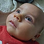 baby, infant, face, eyes, eyelashes, nose, mouth, cheeks, skin, head, ear, red_shirt, clothing, blanket, bed, portrait, close_up, gaze, cuteness, soft_lighting