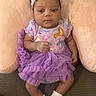 baby, baby_girl, child, clothing, colorful, cushion, cute, flower_pattern, happy, headband, indoors, infant, onesie, portrait, purple, seated, small, socks, soft_texture, tutu