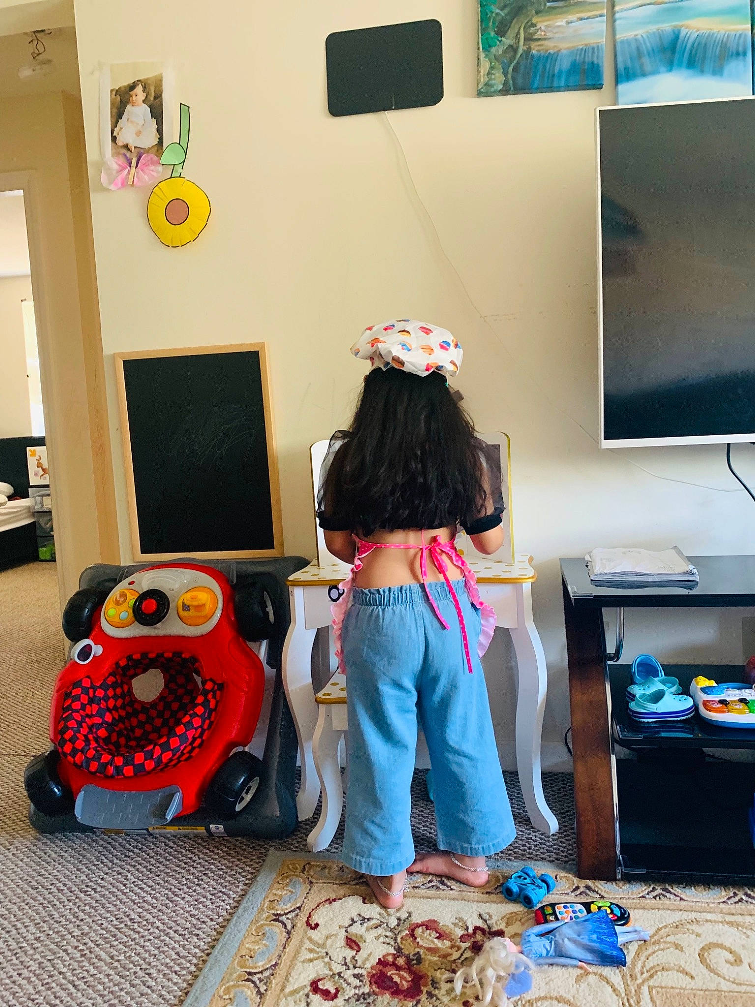 Eva is registered to the contest to win money with this photo: art, audio_equipment, backpack, bag, bedroom, child, display_device, flooring, home_appliance, human_leg, linens, living_room, luggage_and_bags, person, play, room, t_shirt, television, television_set, visual_arts