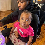Aaliyah is registered to the contest to win money with this photo: baby, child, person, adult, cake, frosting, kitchen, food, table, plate, floor, cat, clothing, tutu, pink_shirt, sitting, holding, indoor, wooden_floor, curly_hair