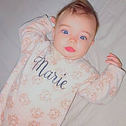 Esmée a rejoint le concours — aidez-le/la à gagner de superbes lots ! baby, infant, blue_eyes, onesie, cat_pattern, bed, blanket, remote_control, curly_hair, cute, sleepwear, toddler, person, indoor, soft_lighting, expression, lying_down, hand, face, pink_lips