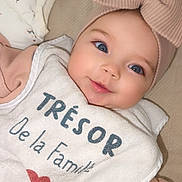 Esmée a rejoint le concours — aidez-le/la à gagner de superbes lots ! baby, bib, blanket, blue_eyes, bow, closeup, clothing, cute, face, happy, headwear, heart, indoors, infant, person, portrait, sleepwear, smiling, soft_toys, text