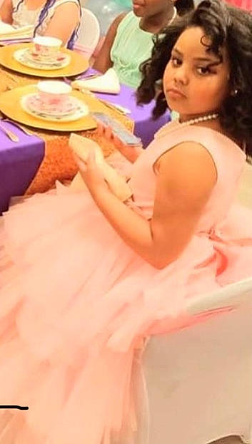 Makiyah is registered to the contest to win money with this photo: blurred, chair, child, dress, event, finger, fun, hair, happy, human_leg, leisure, nail, peach, person, pink, plate, sitting, table, tableware, thigh