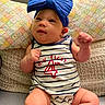Avalon is registered to the contest to win money with this photo: baby, child, infant, blue_bow, headband, striped_clothing, onesie, sitting, couch, pillow, patterned_pillow, knitted_blanket, indoor, cute, smiling, fist, face, person, happy, cozy