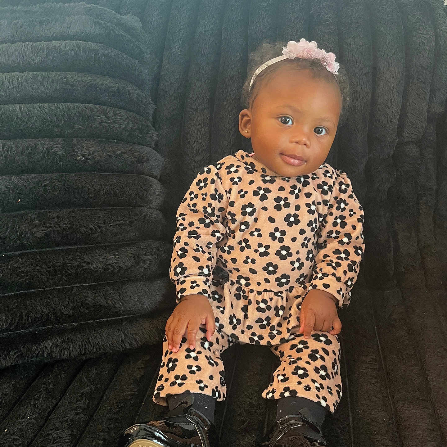 Roriee is registered to the contest to win money with this photo: baby, child, portrait, sitting, couch, indoor, headband, flowers, leopard_print, outfit, fashion, shoes, smiling, dark_background, furniture, home, baby_fashion, black_couch, window_blinds, photography