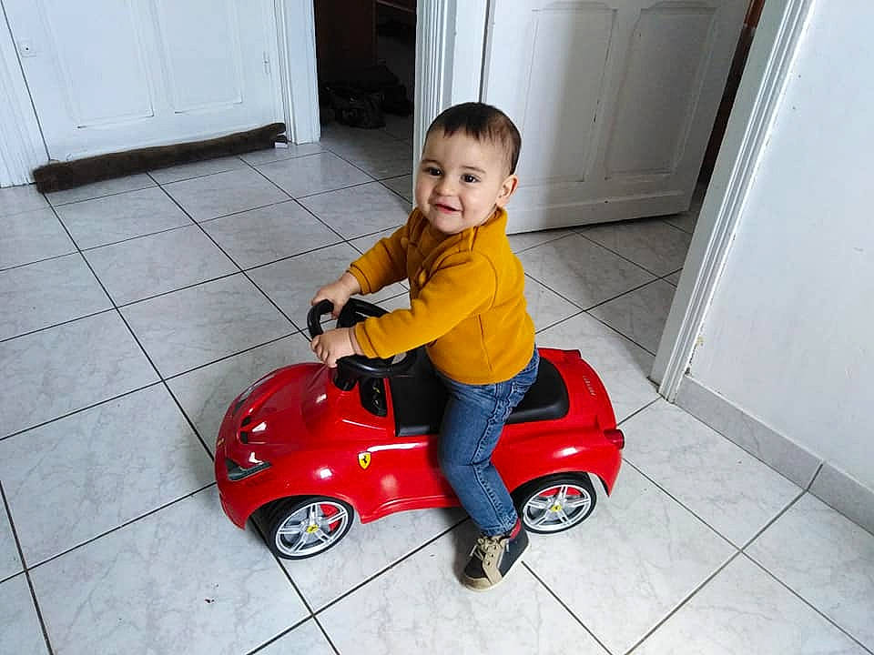 Quentin participe au concours pour gagner de l'argent avec cette photo : child, flooring, person, play, product, red, riding_toy, scooter, smile, toddler, toy, vehicle