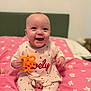 baby, infant, smiling, toy, bed, pink, floral, clothing, cute, child, happy, sitting, indoors, person, head, face, sock, playful, pajamas, bedroom