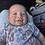 Mateo is registered to the contest to win money with this photo: baby, smiling, infant, onesie, animal_print, clothing, car_seat, backpack, happy, portrait, child, cute, face, person, indoor, seat, soft_light, baby_boy, closeup, comfortable
