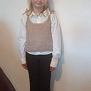 Eden a rejoint le concours — aidez-le/la à gagner de superbes lots ! black_pants, blonde_hair, carpet, casual, child, clothing, feet, floor, girl, indoor, knitted_vest, person, plain_wall, portrait, shadow, smile, standing, white_shirt, white_shoes, young