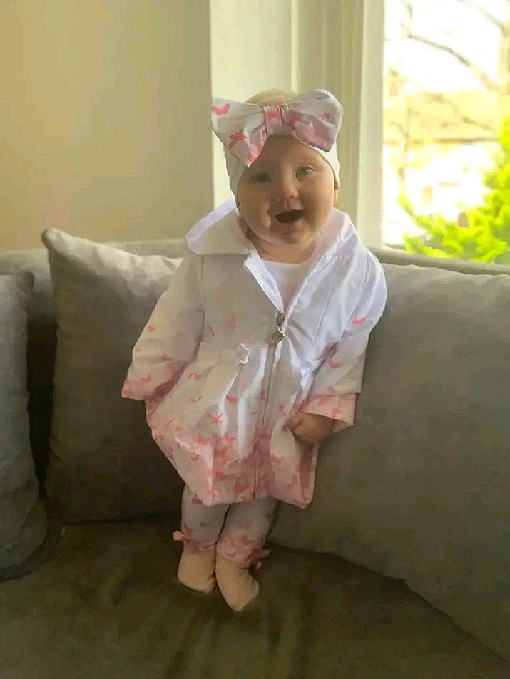 Phoebe joined the competition — help win amazing prizes! baby, baby_toddler_clothing, comfort, couch, face, floor, flooring, fur, gesture, happy, headwear, linens, mammal, person, room, sitting, sleeve, smile, textile, thumb