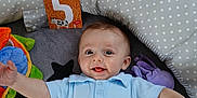 Iloan a rejoint le concours — aidez-le/la à gagner de superbes lots ! baby, child, smiling, blue_shirt, play_mat, toys, polka_dot, cushion, floor, wooden_floor, green_ball, stuffed_animal, purple_toy, happy, lying_down, infant, portrait, indoor, cute, polo_shirt