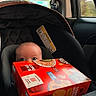 Luca is registered to the contest to win money with this photo: baby, car_seat, child, box, crackers, car_interior, window, seatbelt, curious, face, head, infant, safety, travel, vehicle, seat, child_safety, bright_colors, red_box, looking