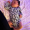 Naomi joined the competition — help win amazing prizes! baby, sleeping, infant, leopard_print, onesie, bedspread, floral_pattern, purple_light, peaceful, cute, child, resting, indoors, soft_lighting, human, newborn, face, skin, leg, hand