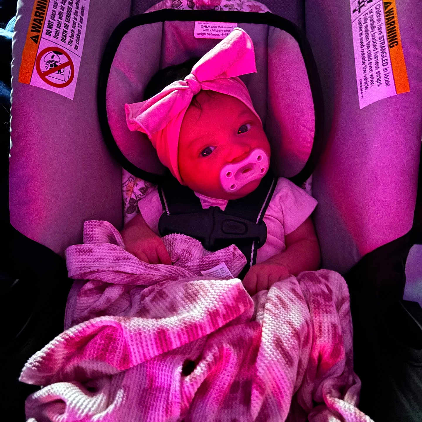 Naomi is registered to the contest to win money with this photo: baby, car_seat, blanket, pacifier, headband, pink_light, infant, child, seatbelt, clothing, portrait, indoors, cute, child_seat, baby_girl, soft_texture, toddler, people, sitting, cozy
