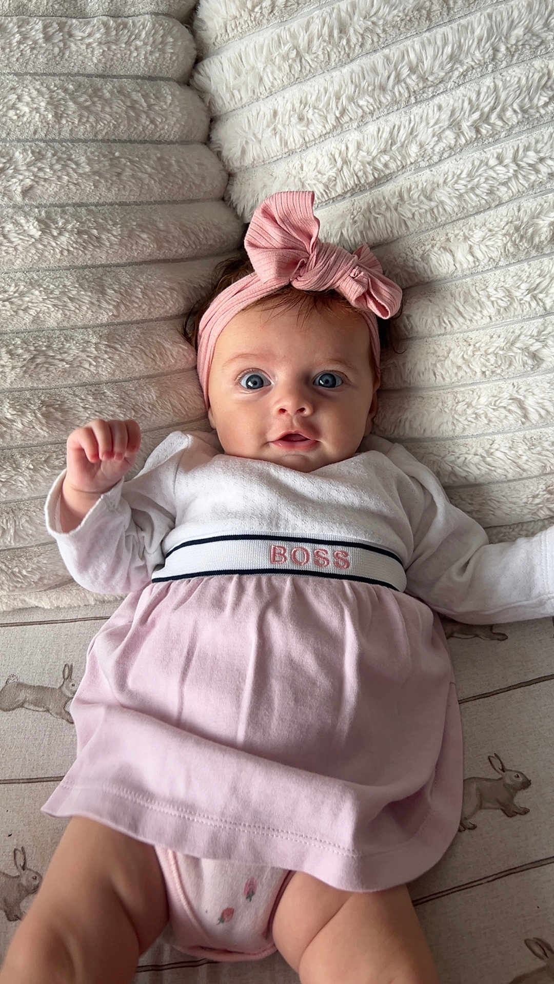 Amelia joined the competition — help win amazing prizes! baby, infant, headband, pink_bow, dress, clothing, lying_down, blanket, soft_texture, bunny_print, cute, wide_eyes, face, child, portrait, indoors, person, adorable, small_hands, looking_at_camera