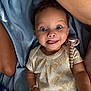 baby, child, smiling, tongue_out, curly_hair, butterfly_pattern, pacifier, blue_blanket, arm, cute, happy, infant, person, lying_down, clothing, indoors, portrait, playful, expression, skin