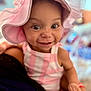 baby, child, pink_hat, striped_clothing, smile, face, eyes, arm, hand, person_holding, indoor, portrait, cute, happy, infant, closeup, soft_focus, warm_lighting, headwear, young_child
