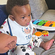 Demari is registered to the contest to win money with this photo: baby, bib, child, clothing, colorful, couch, curly_hair, cute, expression, foot, hand_holding, indoor, infant, mickey_mouse, pajamas, person, play, support, toy, young