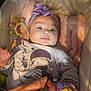 baby, infant, headband, bow, toy, bird_toy, bassinet, blanket, cushion, hand, clothing, purple, cute, child, portrait, indoor, soft_lighting, smile, person, closeup