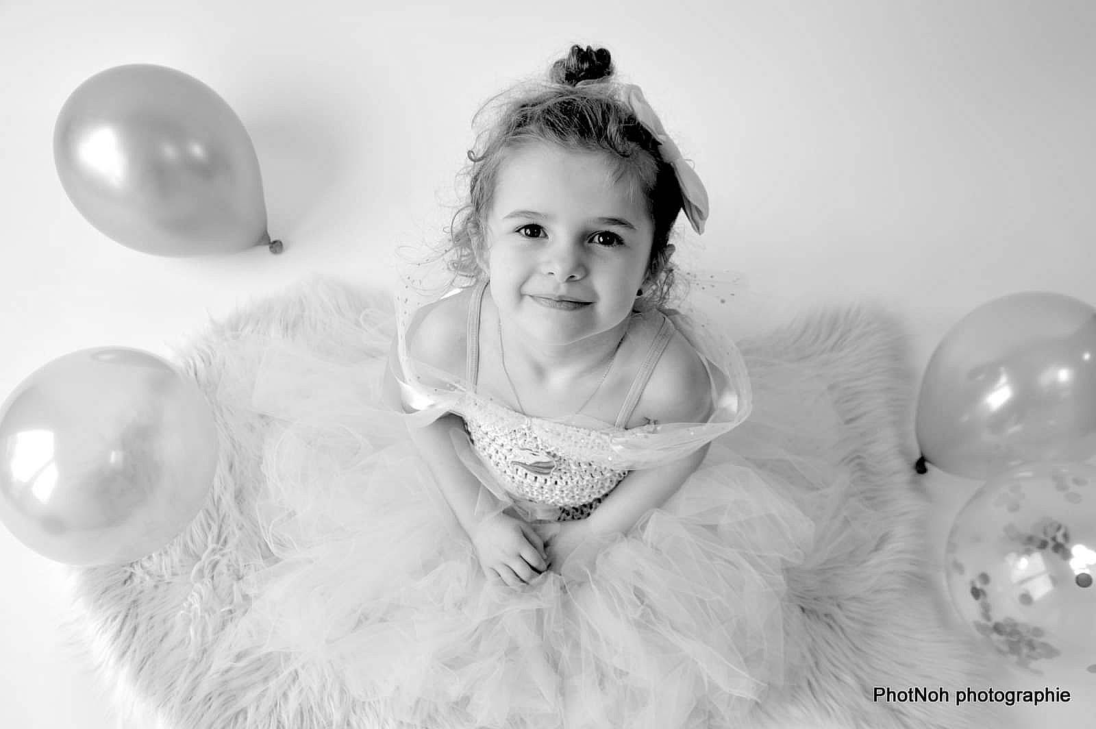 Céléna participe au concours pour gagner de l'argent avec cette photo : baby_toddler_clothing, balloon, black_and_white, child, dress, eye, face, facial_expression, flash_photography, fun, happy, head, iris, joy, monochrome, monochrome_photography, person, smile, standing, style
