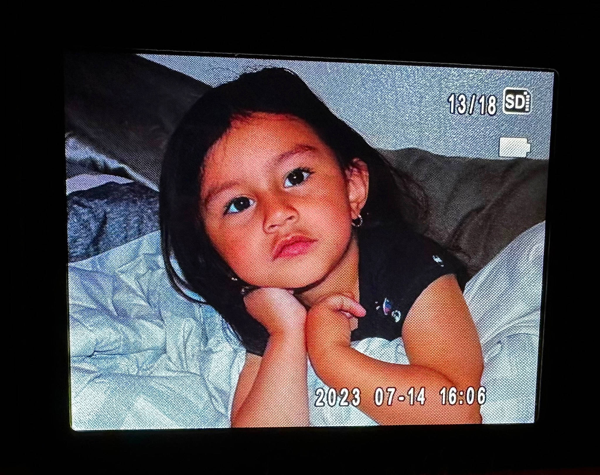 Cataleya is registered to the contest to win money with this photo: baby, baby_toddler_clothing, cheek, child, chin, cool, darkness, display_device, eyelash, flash_photography, flesh, happy, lip, mouth, nose, person, photo_caption, picture_frame, room, skin